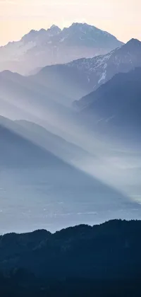 This stunning phone live wallpaper showcases a breathtaking view of an awe-inspiring mountain range, as seen from the top of a hill