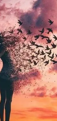 This beautiful live wallpaper showcases a woman standing amidst a flock of birds, set against a captivating sunset