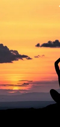 Looking for a Zen-inspired phone live wallpaper? Check out this beautiful and calming scene of a human silhouette in a yoga pose against a stunning sunset background