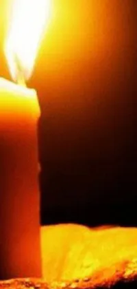 Get a peaceful and calming ambiance on your phone with this live wallpaper featuring a lit candle on a wooden table