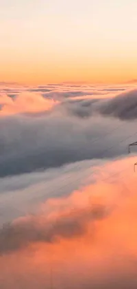 This phone live wallpaper showcases a power line in the center of an orange mist-filled sea of clouds against a stunning aerial view