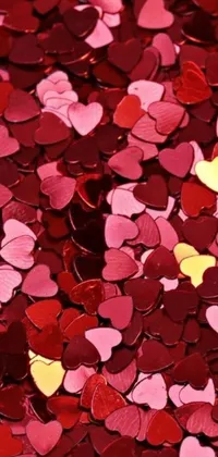 This stunning phone live wallpaper features a beautiful pile of heart-shaped confetti in shades of red and pink, set against a captivating background with metallic accents