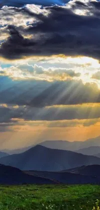 This phone live wallpaper showcases a stunning image of the sun breaking through the clouds above a mountainous landscape