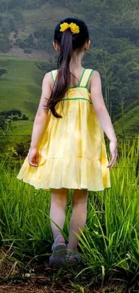 This live wallpaper showcases a beautiful, mountainous landscape with a delightful young girl standing in a luscious, green field