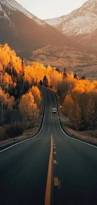 This phone live wallpaper displays a car driving down a road surrounded by mountains