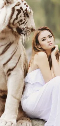 This live wallpaper showcases a stunning white tiger lying next to a woman on a rock