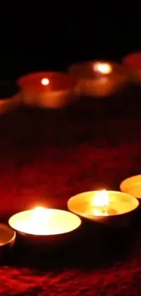 This phone live wallpaper features a beautiful row of flickering candles arranged in the shape of a heart