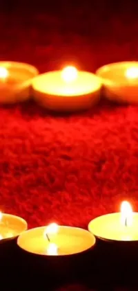 This live wallpaper for your phone showcases a beautiful and serene arrangement of candles in the shape of a heart