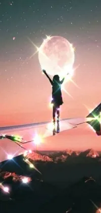 This magical smartphone live wallpaper features a person standing on an airplane wing, leaping with arms raised towards a mystical and healing pink moon