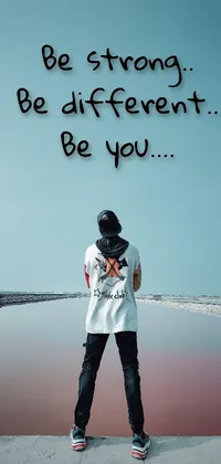 This phone live wallpaper showcases a man confidently standing in front of a serene body of water with words of encouragement - "be strong be different be you" - displayed prominently