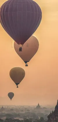 Experience the thrill of watching a group of hot air balloons soar over a city with this stunning live wallpaper