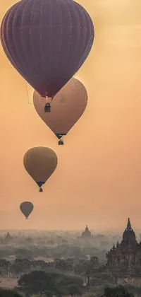 This phone live wallpaper features a group of hot air balloons gently floating in a sky with a narrow mountain range in the background