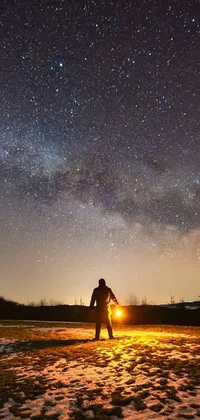 This stunning live wallpaper features a man standing on a snow covered field, raising his hands in the air