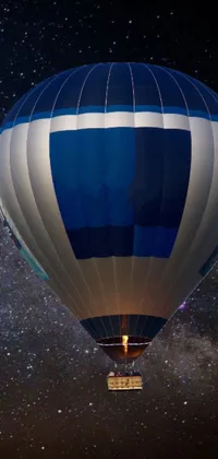 This stunning live wallpaper depicts a blue and white hot air balloon gliding serenely through the night sky against the backdrop of a mesmerizing galaxy-themed background