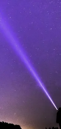 This phone live wallpaper features a beautiful purple sky scene captured in a middle close-up with a solitary figure standing atop a rolling hill