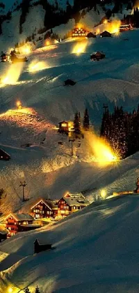 Enjoy the snowy beauty of a lit ski resort at night with this stunning live wallpaper