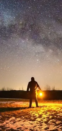 This live wallpaper depicts a snowy field with a man admiring the starry sky above