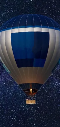 This phone live wallpaper showcases a mesmerizing blue and white hot air balloon drifting through a starry night sky