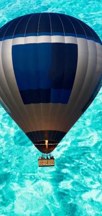Transform your phone screen with this stunning live wallpaper featuring a vibrant and colorful hot air balloon soaring over the peaceful waters of the ocean