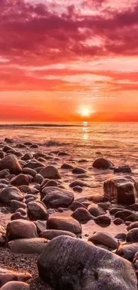 This mobile wallpaper depicts a beautiful sunset over the ocean with rocks in the foreground