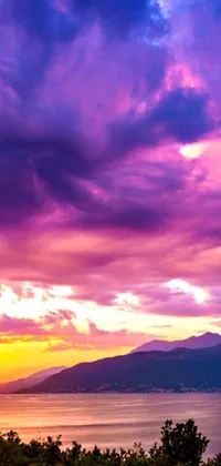 This phone wallpaper showcases a wooden bench atop a lush, green hillside against a backdrop of a breathtaking sunset in hues of violet and yellow with dramatic pink storm clouds adding a touch of drama