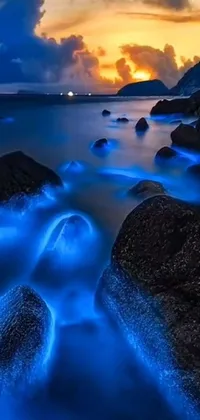 This live wallpaper features a rocky beach next to a serene body of water