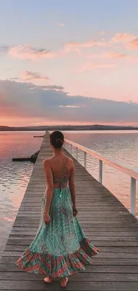 This teal-colored phone live wallpaper depicts a woman strolling a pier on a sunset
