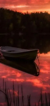 This phone live wallpaper depicts a small boat on a lake with reddish lighting and a stunning sky reflection