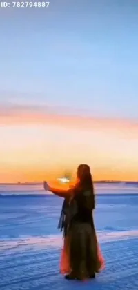 This phone live wallpaper features a woman holding a frisbee in snowy surroundings