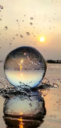 This phone live wallpaper features a stunning glass ball floating atop a tranquil body of water during a stationary evening rain