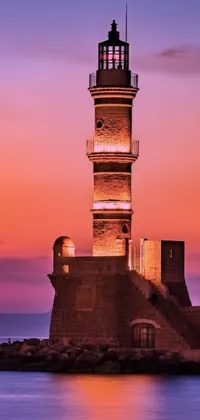 This live wallpaper showcases a stunning image of an old lighthouse standing proudly amidst a calm body of water, with the picturesque town of Mardin in the background