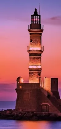 This live wallpaper showcases a charming scene of a lighthouse standing tall in a serene body of water, with the picturesque old town of Mardin serving as the backdrop