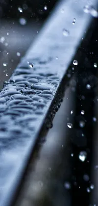 This live phone wallpaper depicts a metal rail in the rain, with water droplets creating a sparkling effect on the surface