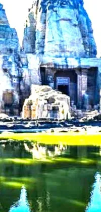 This phone live wallpaper showcases a breathtaking rendering of a serene body of water with visible rocks complemented by Kailasa Temple in the background