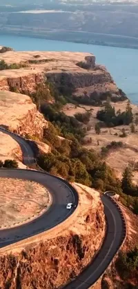 This phone live wallpaper showcases the serene and picturesque beauty of Oregon with a car driving down a winding road along a stretch of water