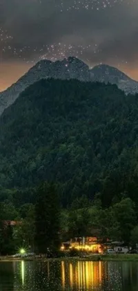 This live wallpaper depicts a stunning scene of a mountain and water body surrounded by green forest