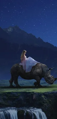 This live phone wallpaper depicts a stunning scene of magic realism featuring a woman sitting on top of a rhino beside a majestic waterfall