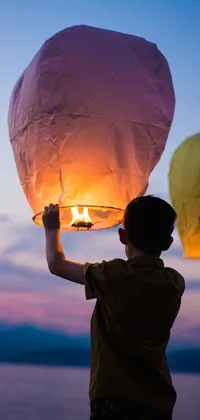 This live wallpaper showcases a serene dawn sky as the backdrop with a couple holding up a sky lantern that emits a warm glow