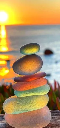 This phone live wallpaper features a stack of rocks on a wooden bench, enhanced by a beautiful sunset in warm tones