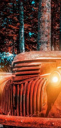 This live phone wallpaper showcases an old rustic red truck parked in the woods at night, surrounded by lumberjack equipment and trees