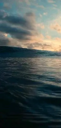 This phone live wallpaper by Pixar depicts a captivating scene of a surfer riding a colossal wave in the ocean at sunrise/sunset