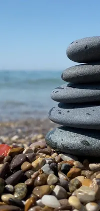 Enhance your phone's display with this mesmerizing live wallpaper featuring a stack of smooth rocks on a serene beach, sourced from Pexels
