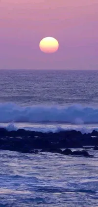 This live wallpaper depicts a stunning sunset over the ocean with waves gently crashing along the shore