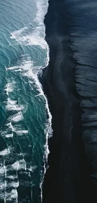 This phone live wallpaper showcases a stunning aerial view of a black sand beach split in half