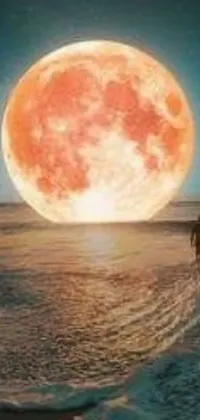 This surreal live wallpaper features a striking scene of a man standing on a beach, gazing up at a giant crimson moon in the sky