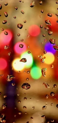 This phone live wallpaper features a captivating image of a raindrop-speckled window, radiating a sense of warmth with its vibrant hues and colorful lights