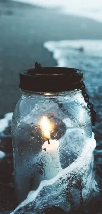 This live phone wallpaper captures the perfect beach scene with a candle sitting on the sand, beside the calming ocean waves