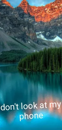 Looking for an eye-catching live phone wallpaper to remind you to disconnect? Look no further than this awe-inspiring scene, featuring a tranquil lake, majestic mountains, and a mobile phone with an intense picture overlay