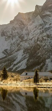 This live wallpaper displays a beautiful mountain range, a clear blue lake, and a charming building against a golden sunburst