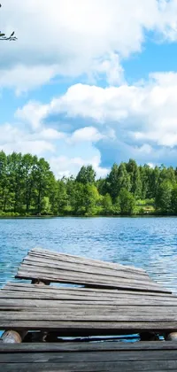 This phone live wallpaper showcases a serene and picturesque wooden dock sitting amidst a breathtakingly beautiful lake